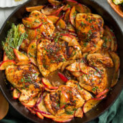 Apple Chicken in a cast iron pan shown from overhead sitting on a green cloth.
