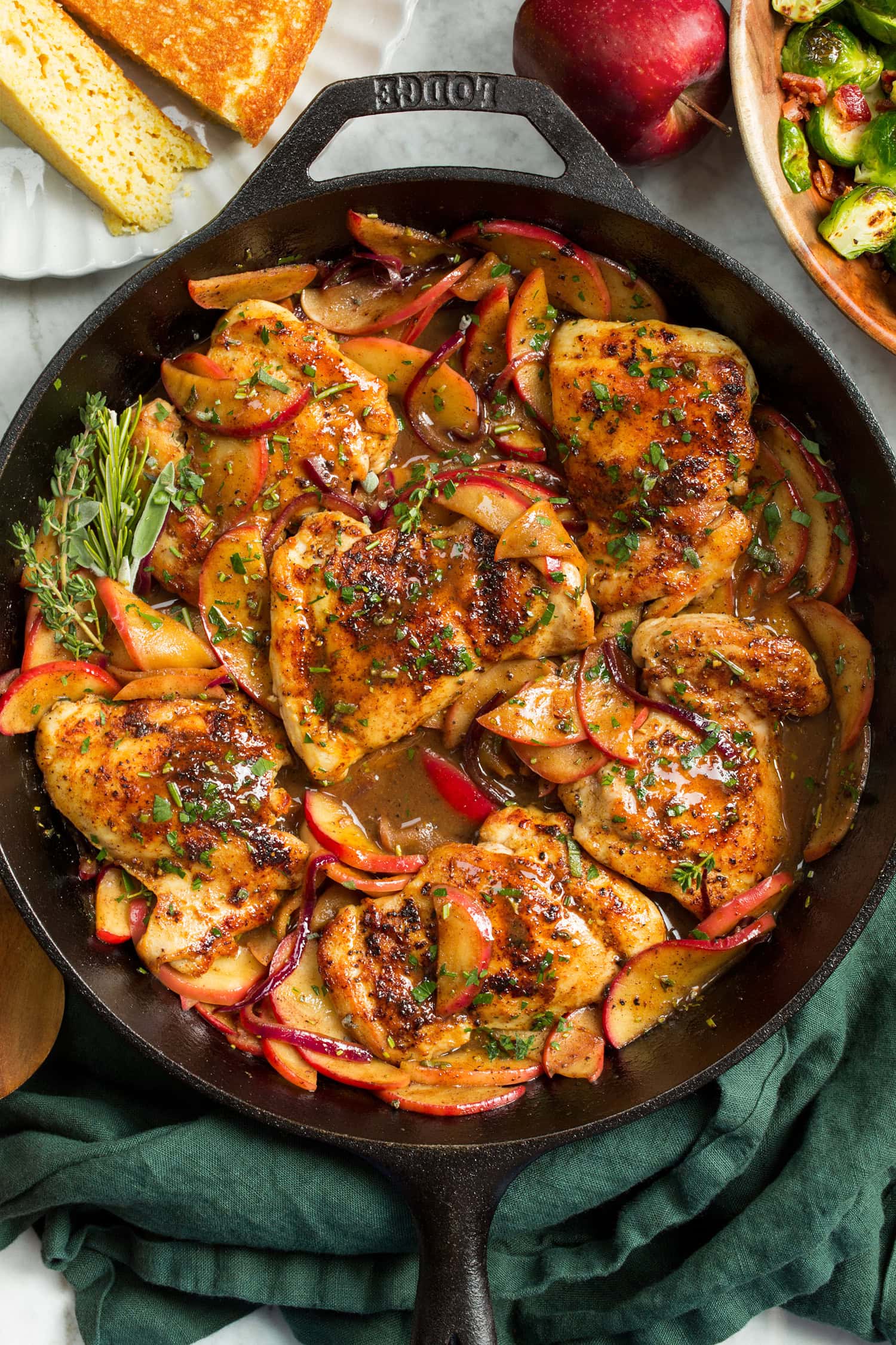 Apple Chicken in a cast iron pan shown from overhead sitting on a green cloth.
