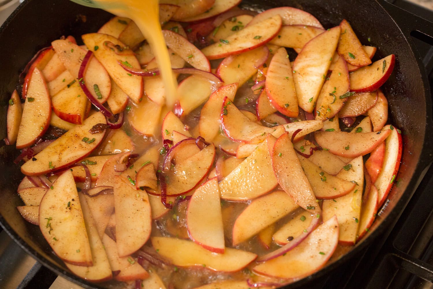 Apples shown after sautéing in butter with apple juice being added to create a pan sauce.