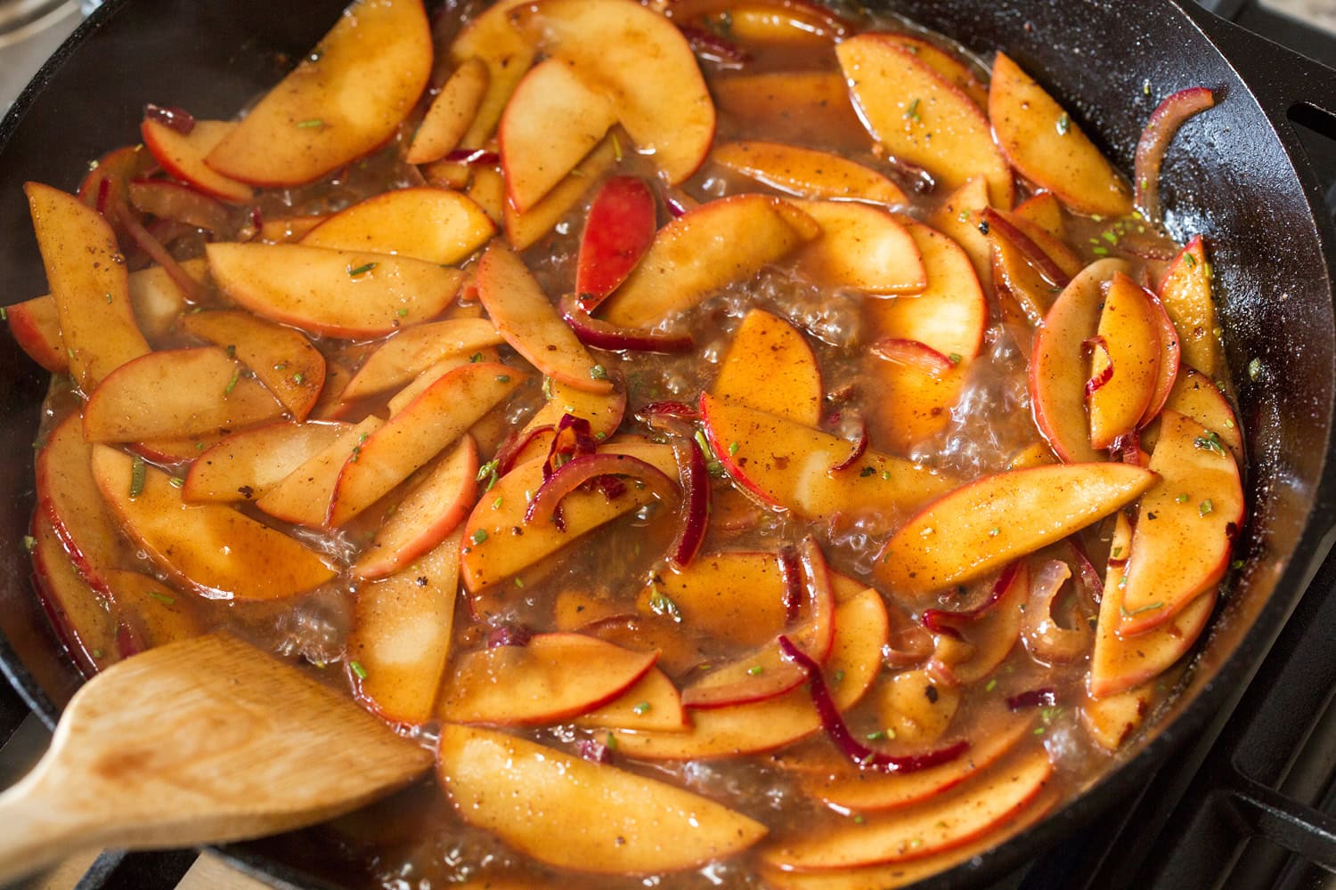 Apples simmering in pan sauce to soften.