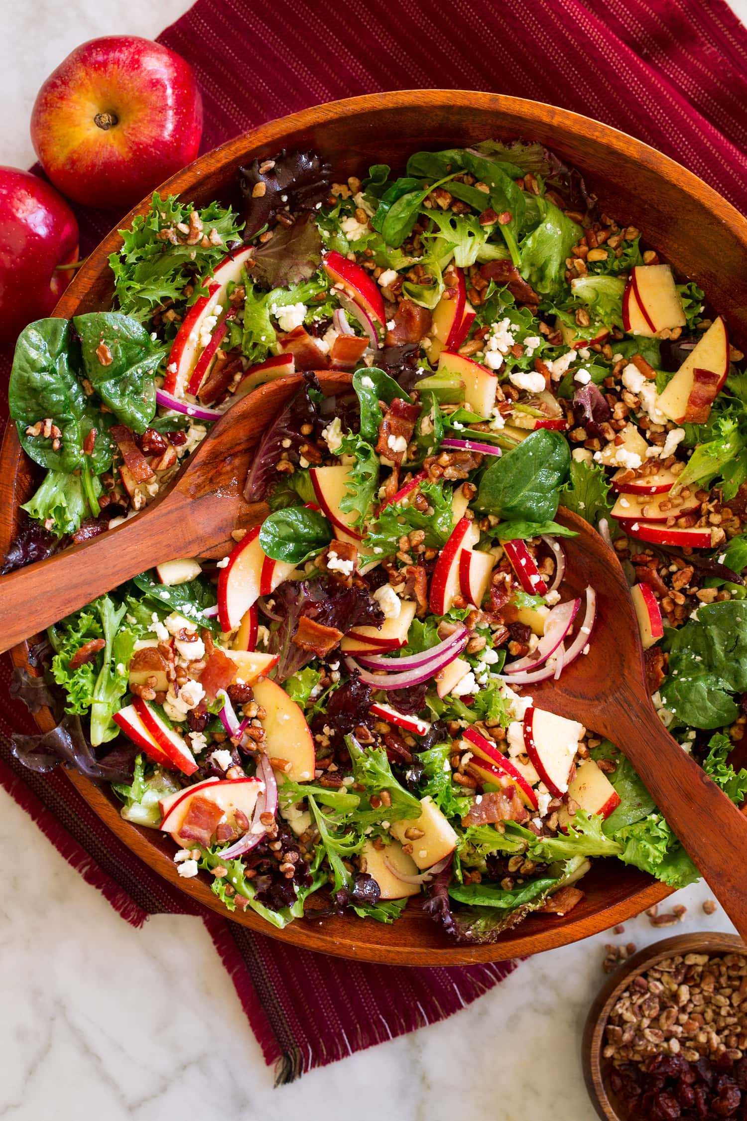 Apple Salad Overhead photo of apple salad in a wooden serving bowl with wooden serving spoons.