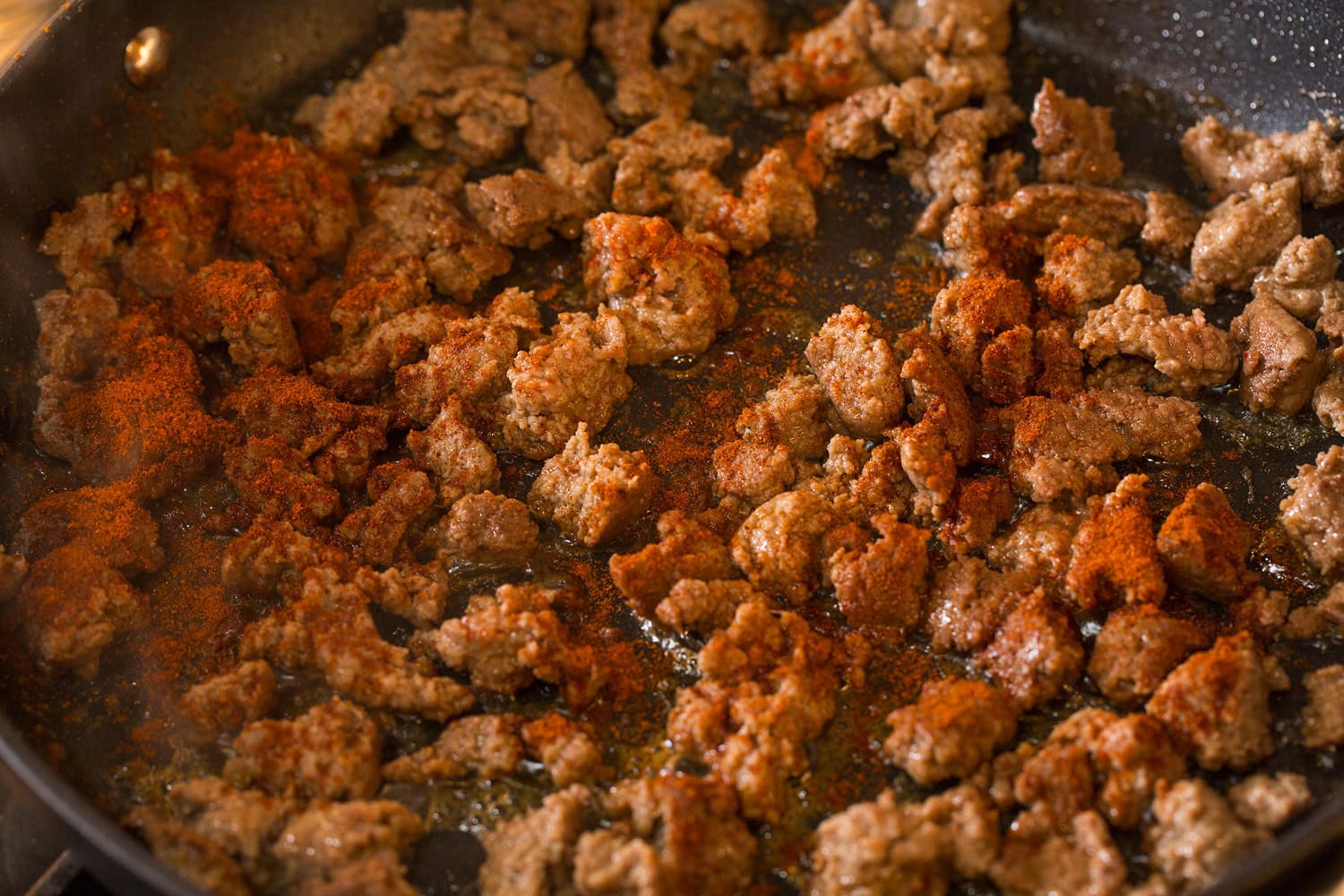 Seasonings added to cooked turkey sausage in skillet.