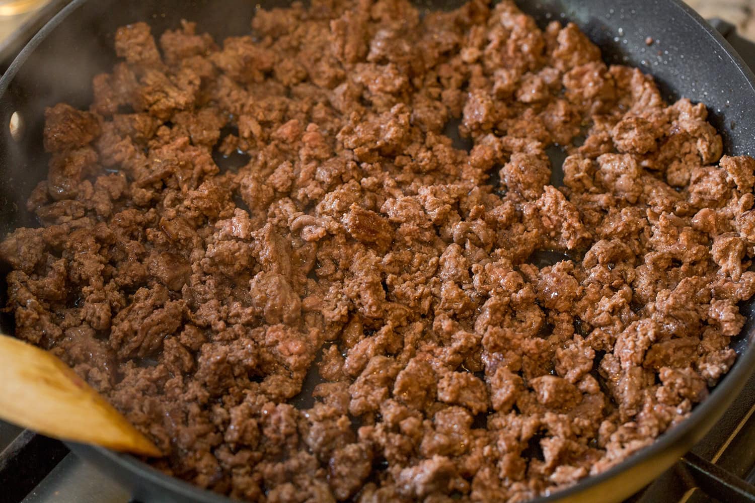 Crumbled cooked beef in skillet.