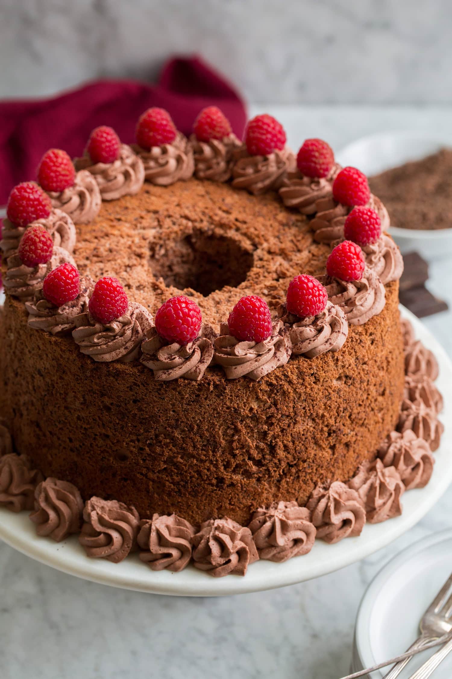 Chocolate angel food cake garnished with raspberries and chocolate whipped cream.