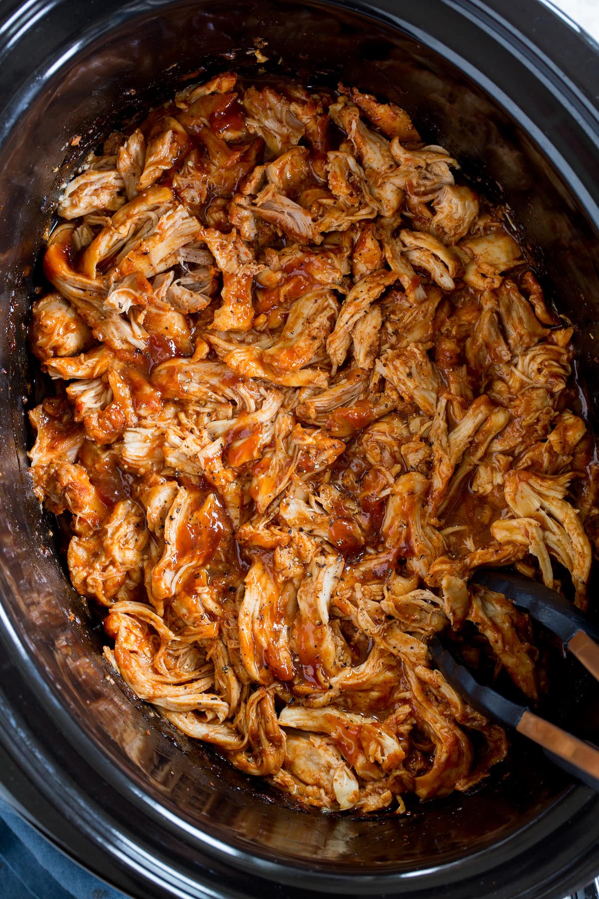 Crockpot BBQ Chicken Photo: Slow cooker barbecue chicken in a black oval crockpot insert. Shown from overhead.