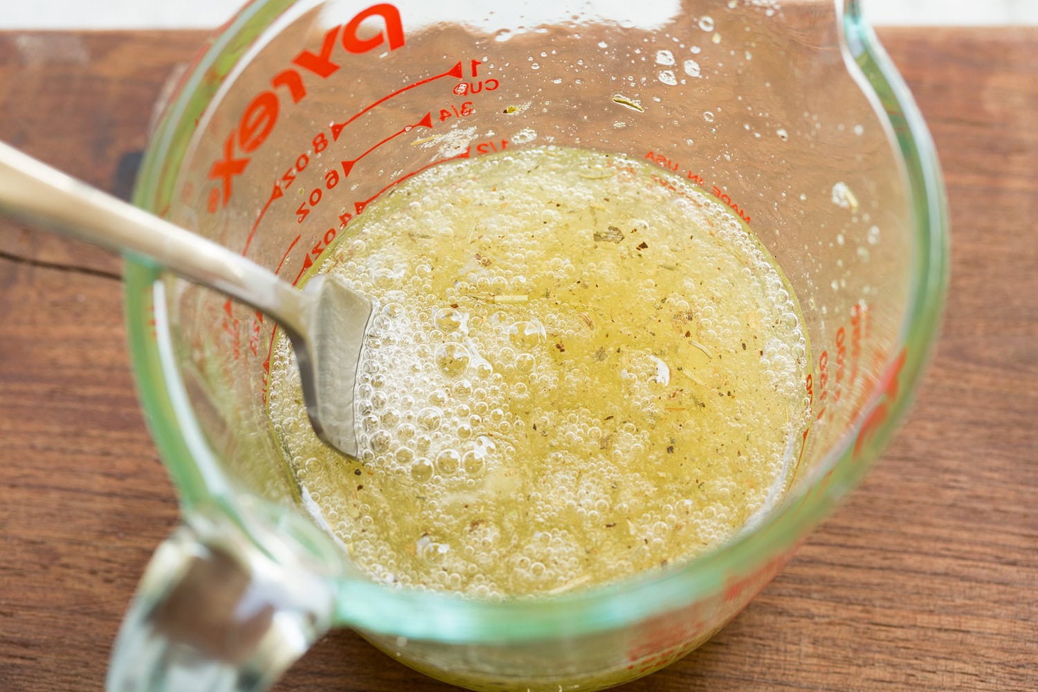 Egg whites being mixed with dried herbs and garlic powder in a glass dish.