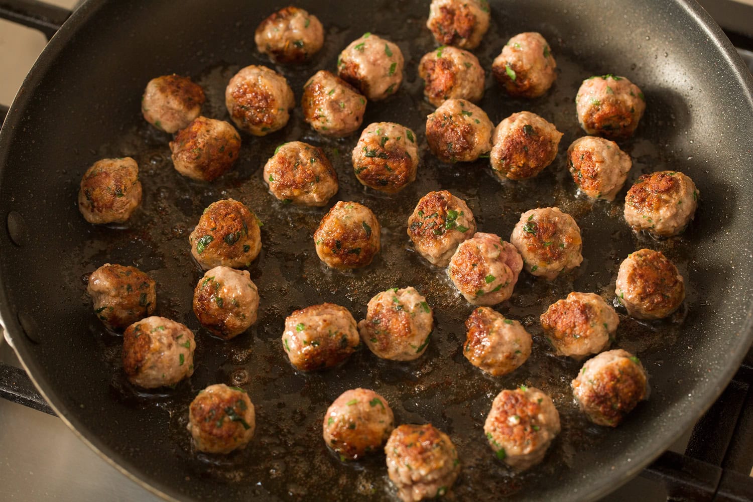 Italian Wedding Soup Browned mini meatballs in a skillet.