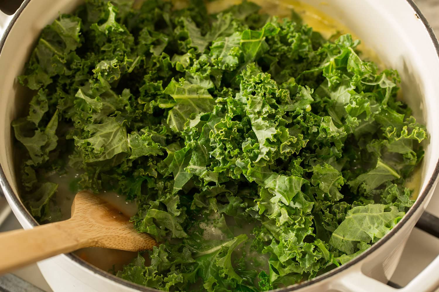 Fresh kale added to pot of soup.
