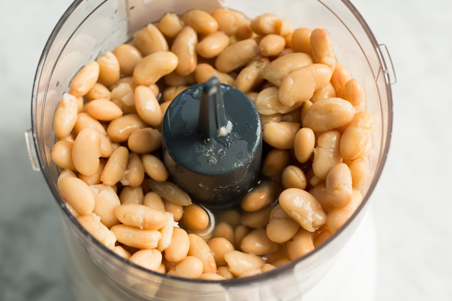 White beans and broth in a food processor before pureeing.