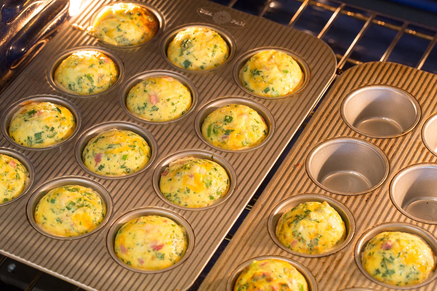Mini Quiche Mini quiches baking in two muffin pans in oven.