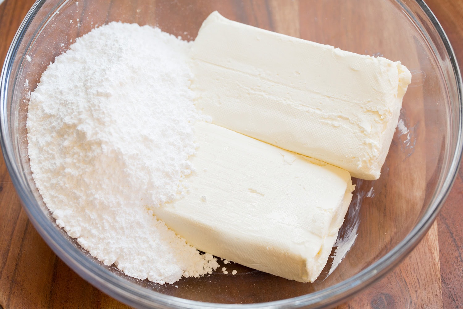 No Bake Cheesecake Cream cheese and powdered sugar in glass mixing bowl.