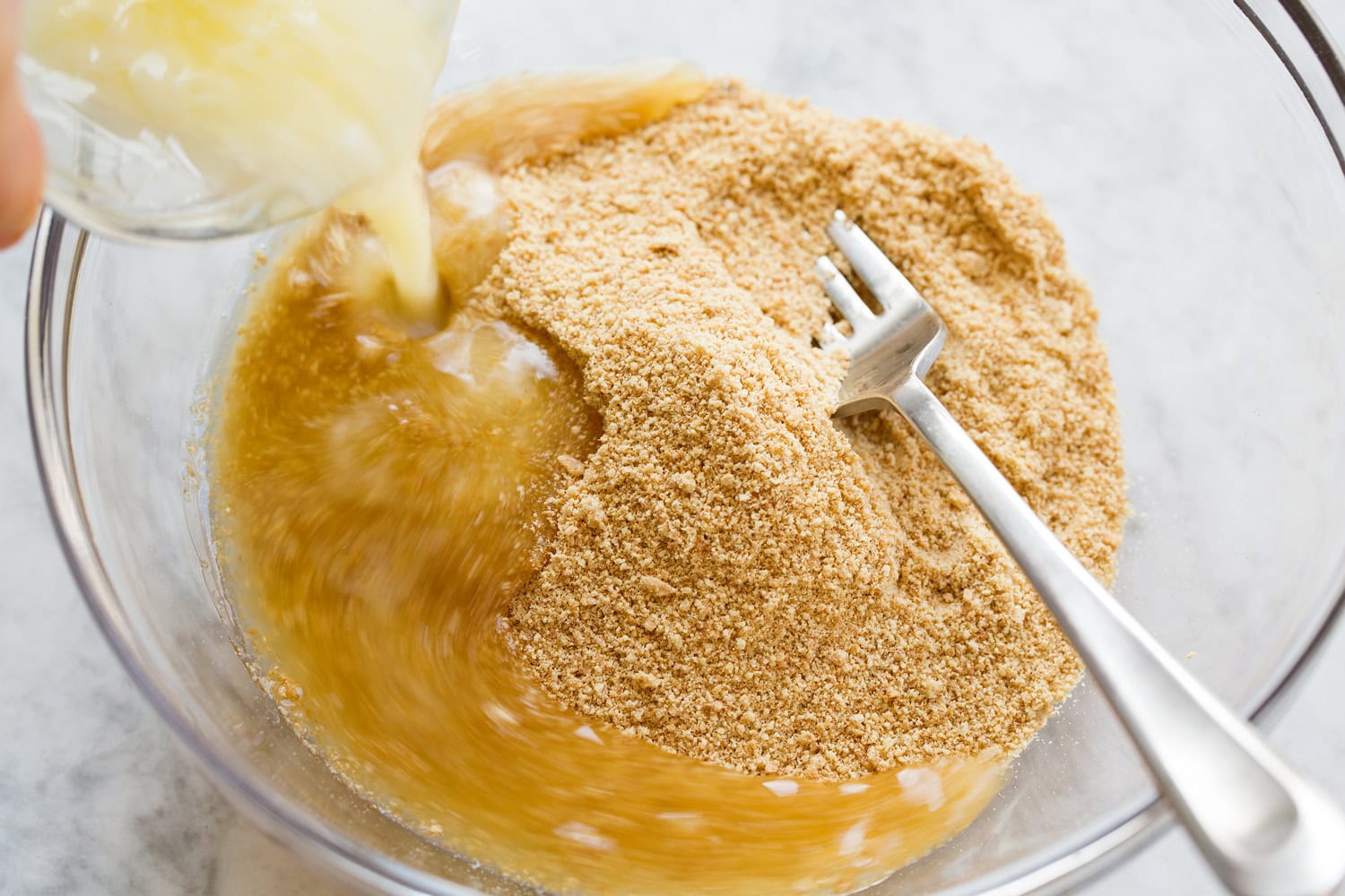 No Bake Cheesecake Graham cracker crumbs with melted butter being added.