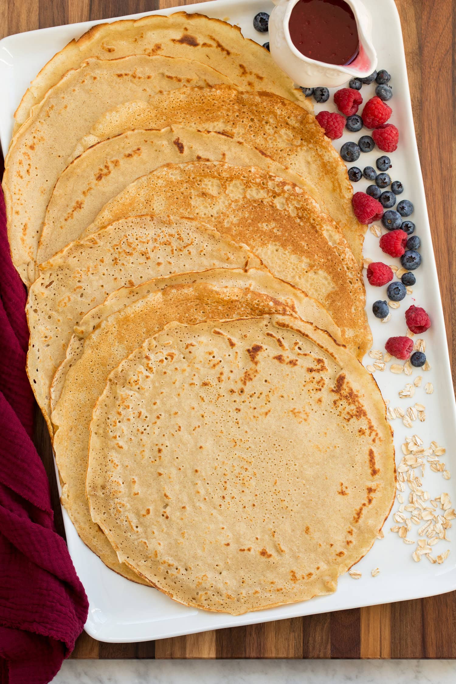 Healthy Oat Crepes Oat flour crepes shown on a white rectangular platter with fresh fruit to the side.