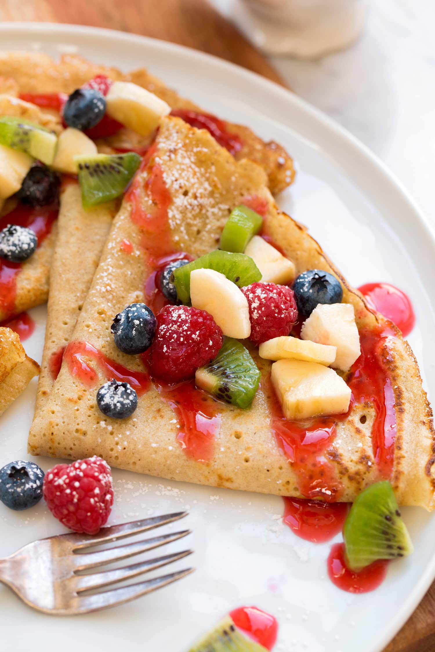 Healthy Oat Crepes Close up photo of healthy oat crepes with chopped fruit and berry syrup.