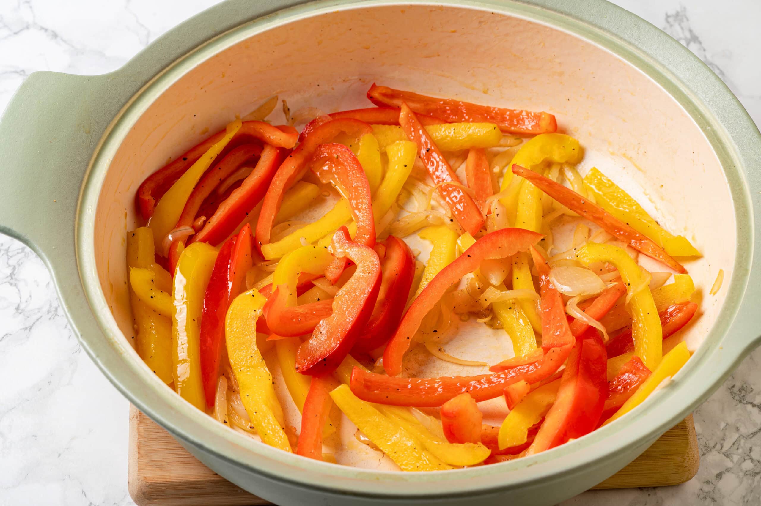 Sautéing bell peppers and onions in a skillet.