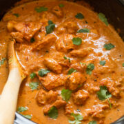 Slow cooker chicken tikka masala garnished with cilantro in a black crockpot.