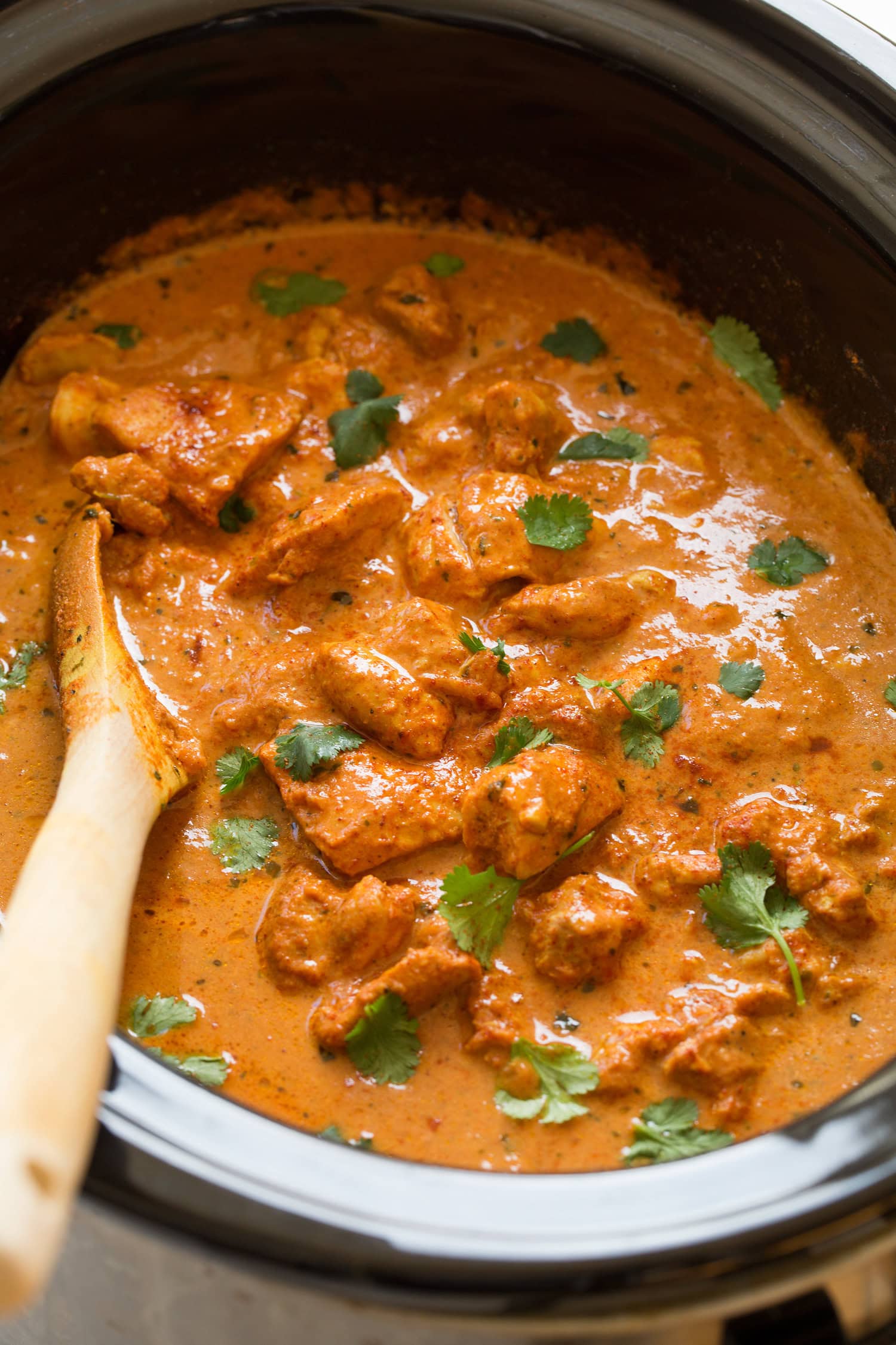 Slow Cooker Chicken Tikka Masala Slow cooker chicken tikka masala garnished with cilantro in a black crockpot.