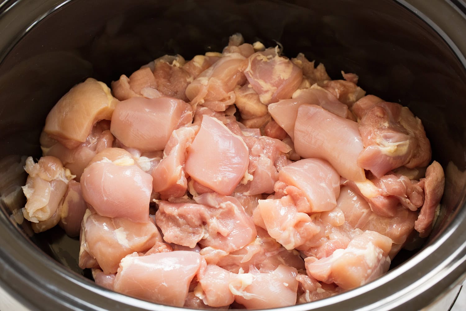 Slow Cooker Chicken Tikka Masala Chicken thighs cut into chunks in a crock pot.