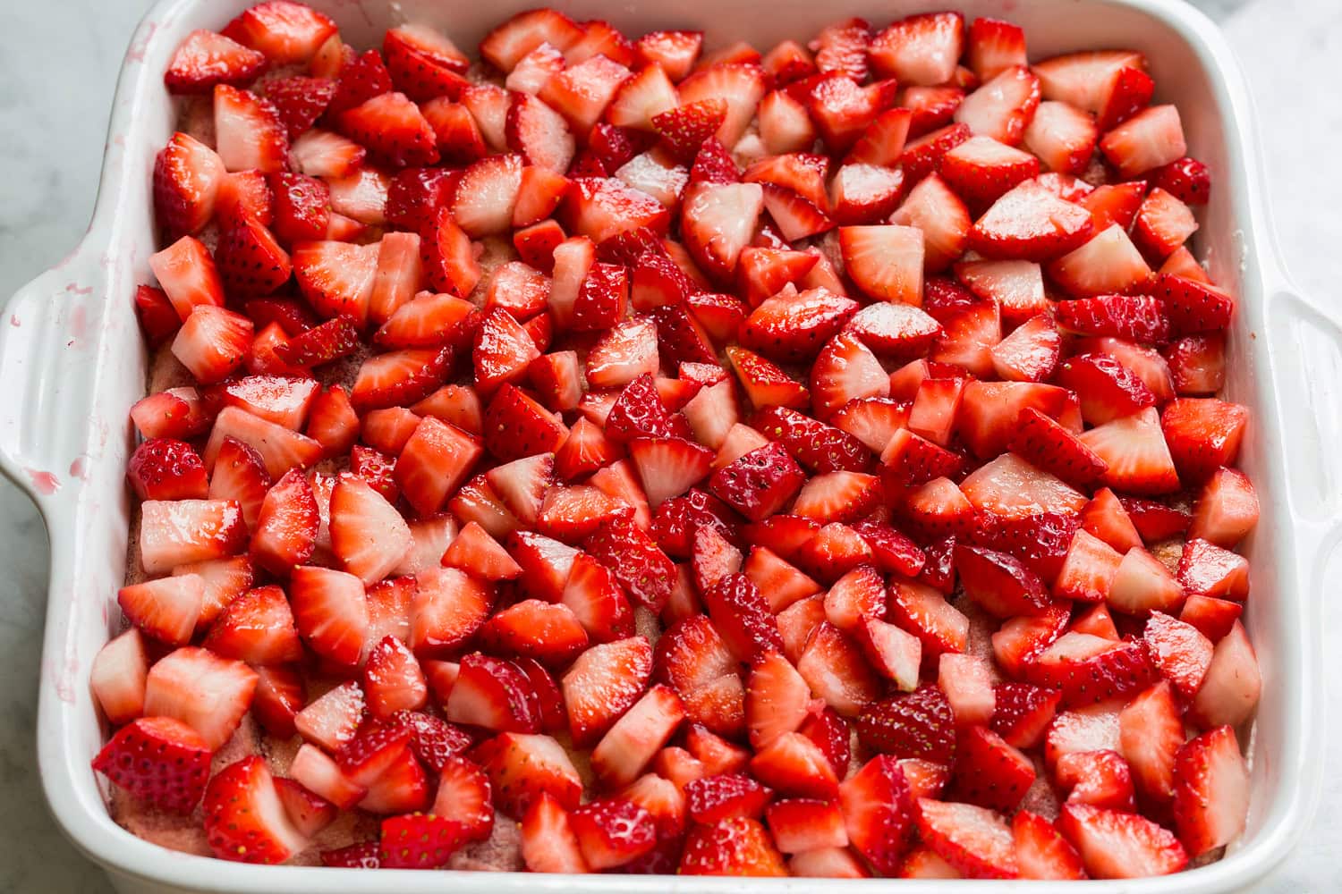 Diced strawberries layered in to baking dish over lady fingers