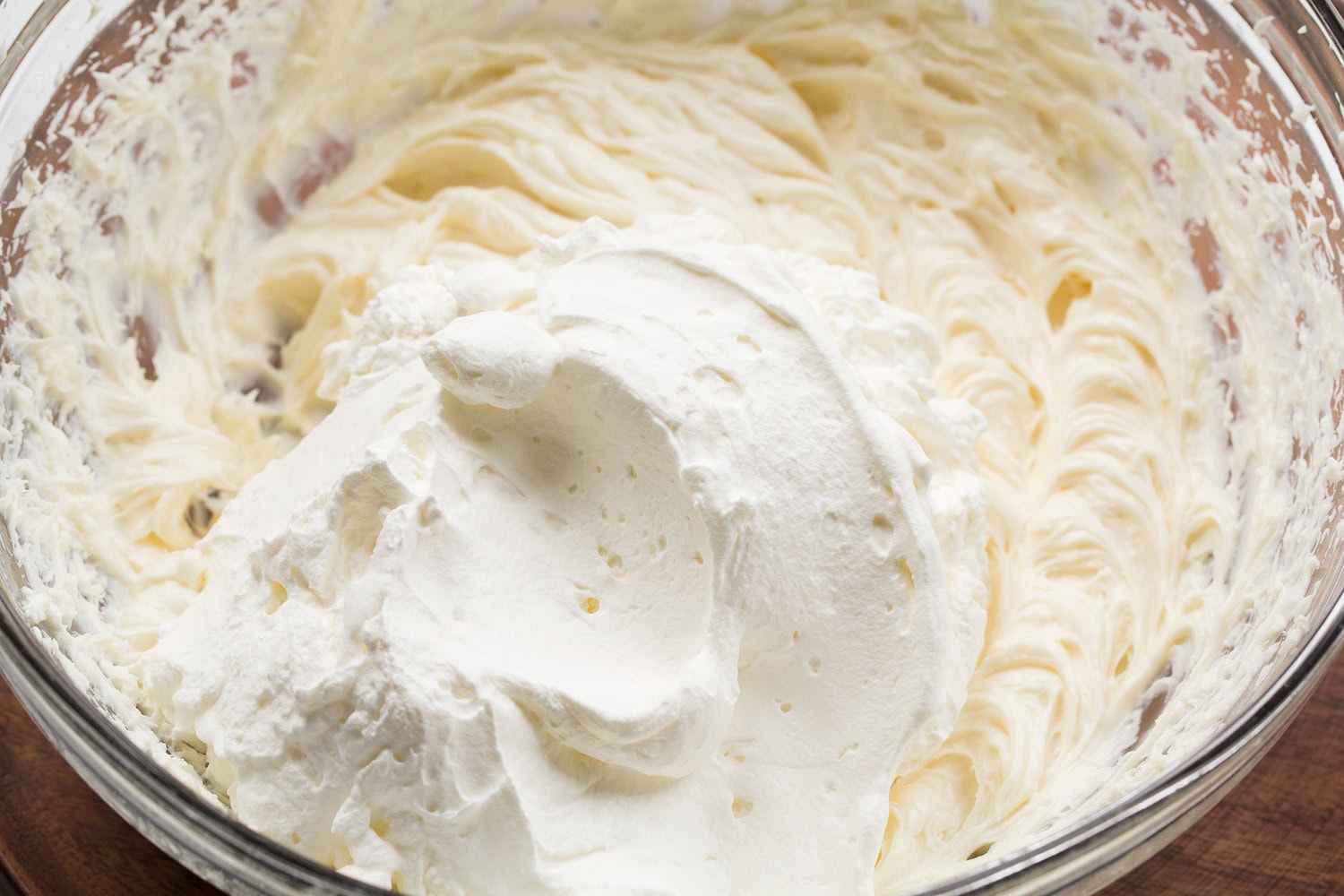Cream cheese and whipped cream added together in bowl.