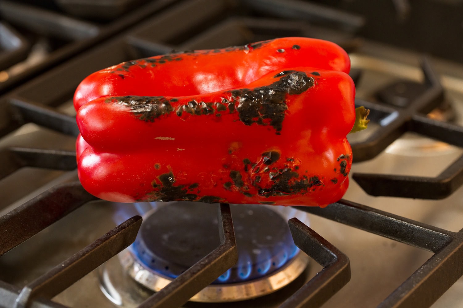 Tortellini Pasta Salad Bell pepper being roasted over flame of gas stove.