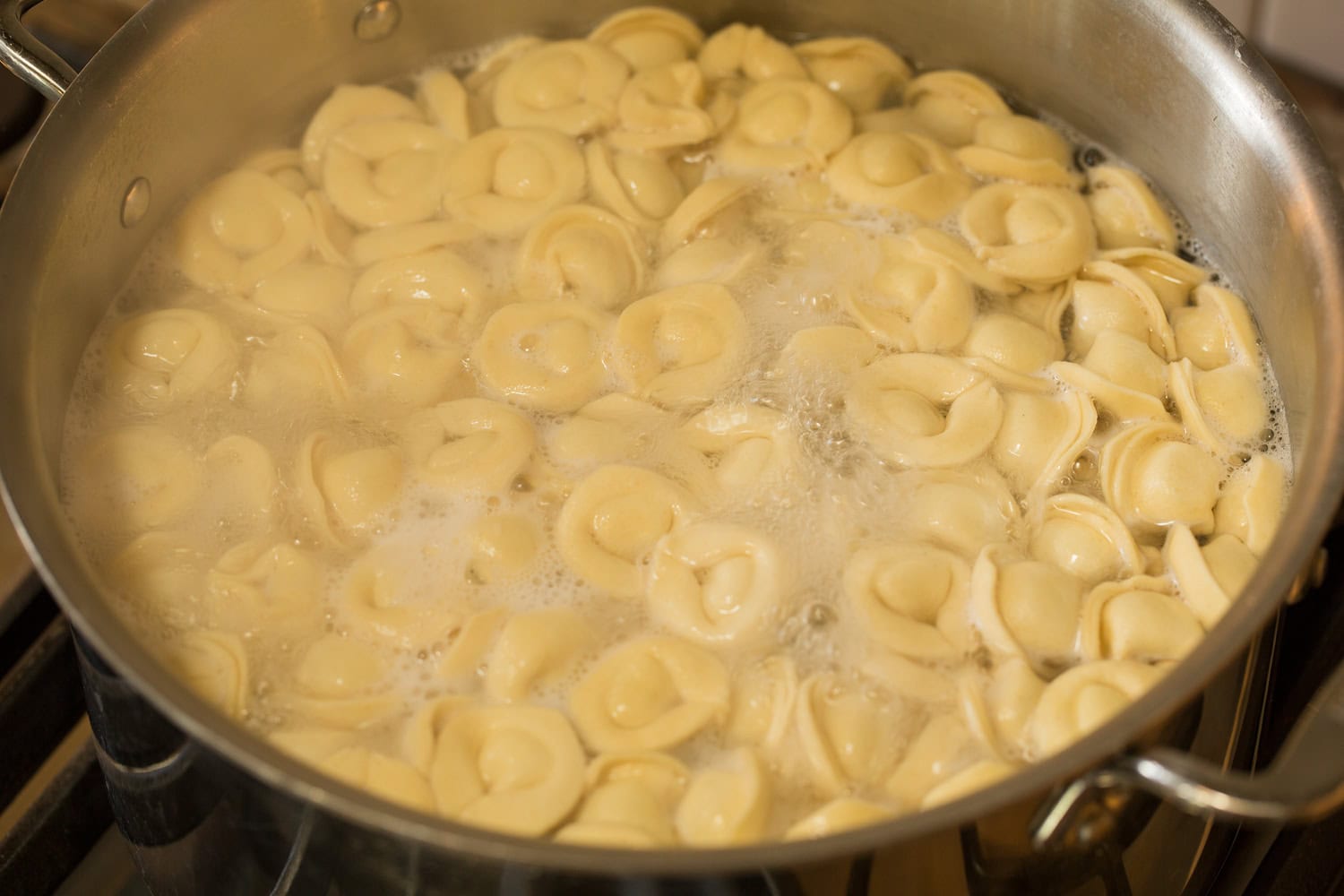 Tortellini Pasta Salad Tortellini being cooked in boiling water in a stainless pot.