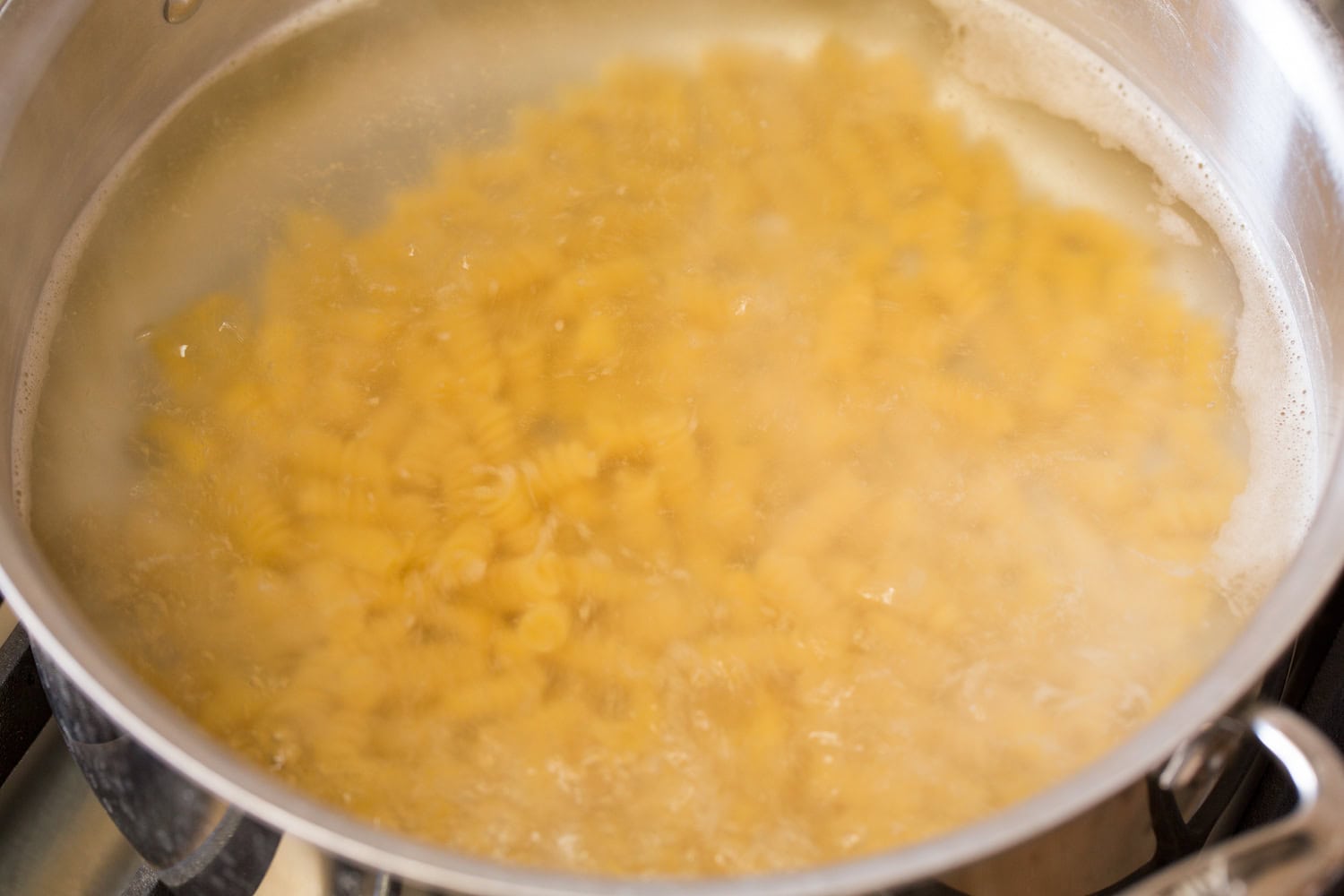 Pasta boiling in a large stainless steel pot.