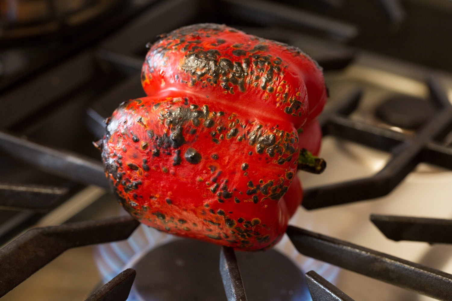 A bell pepper being roasted over a gas stove flame.