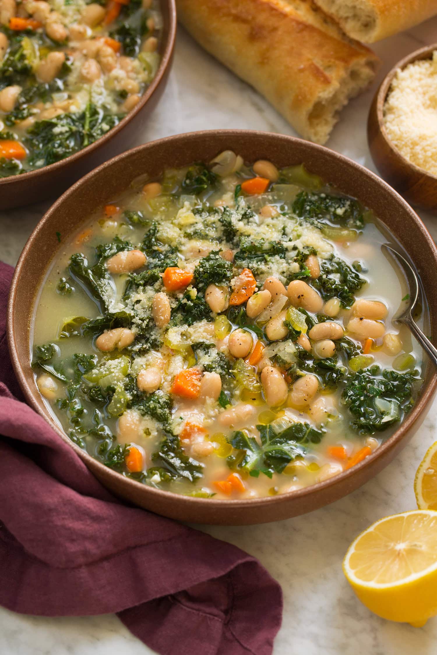 Serving of white bean and kale soup in a brown bowl.
